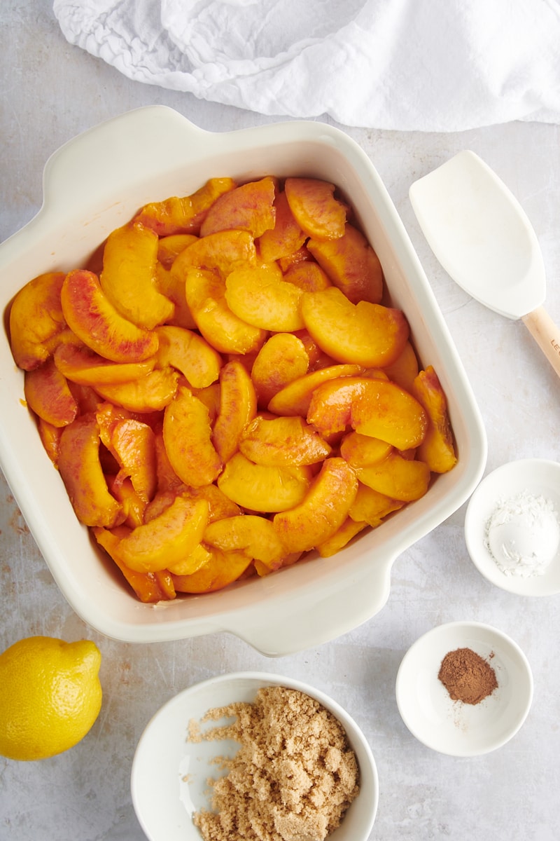 overhead view of sliced peaches in a white baking pan