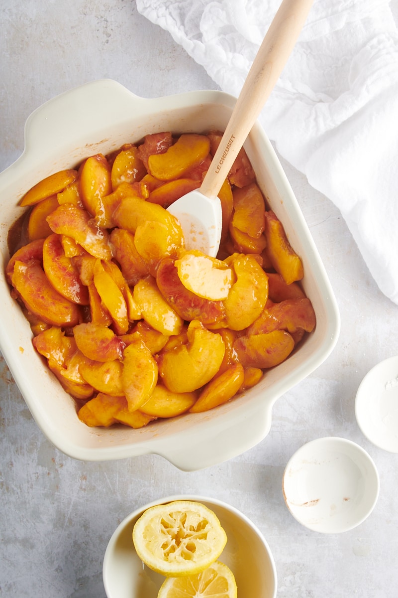 overhead view of mixed peach crisp filling in a white baking pan