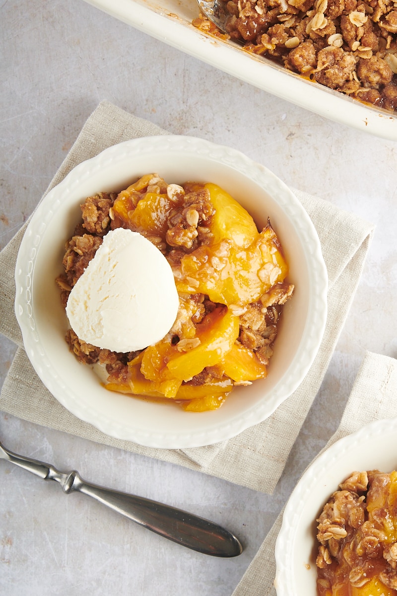 overhead view of a serving of peach crisp topped with ice cream