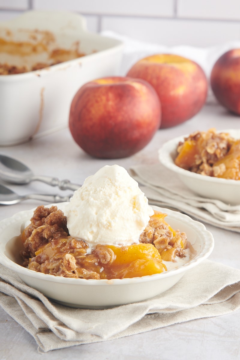 Peach Crisp served in a white bowl and topped with ice cream