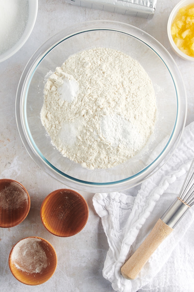 overhead view of flour, baking powder, baking soda, and salt in a glass mixing bowl