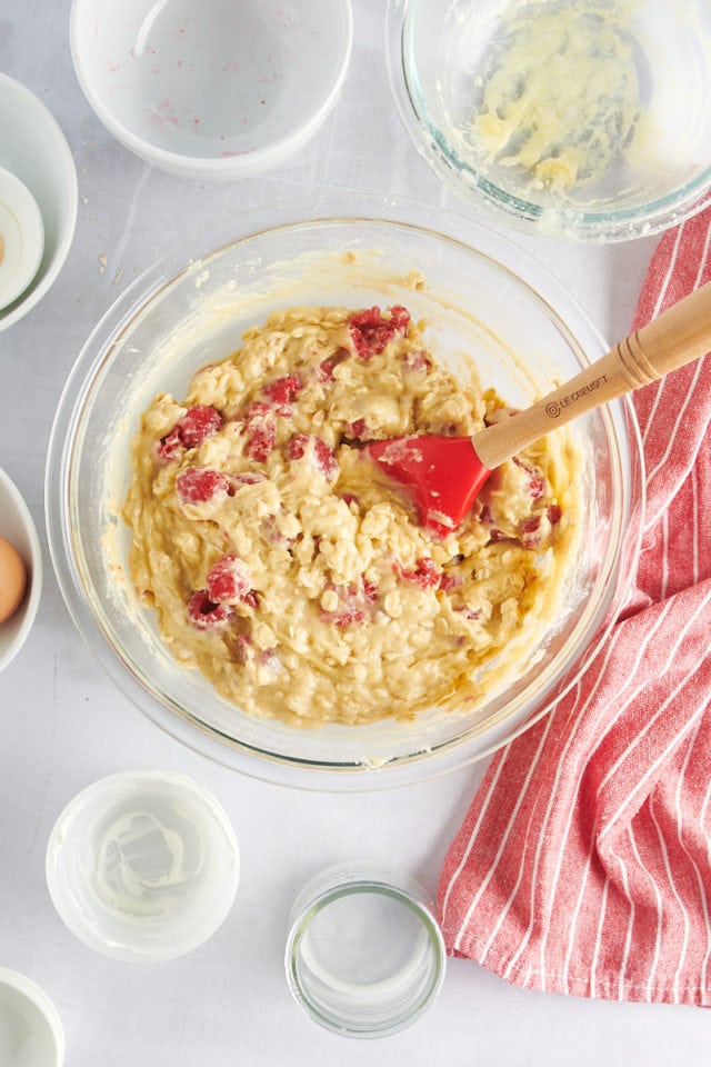 Raspberry oat muffin batter in glass mixing bowl