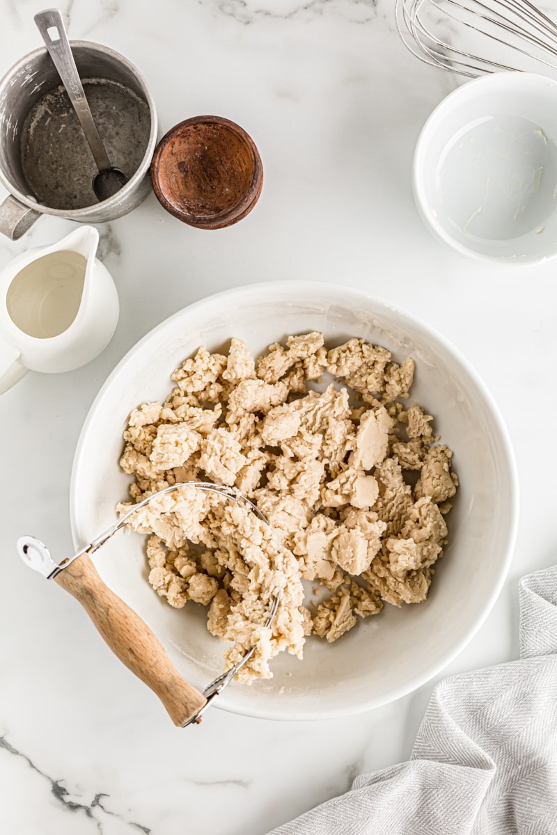 Overhead view of pie dough in bowl with pastry blender