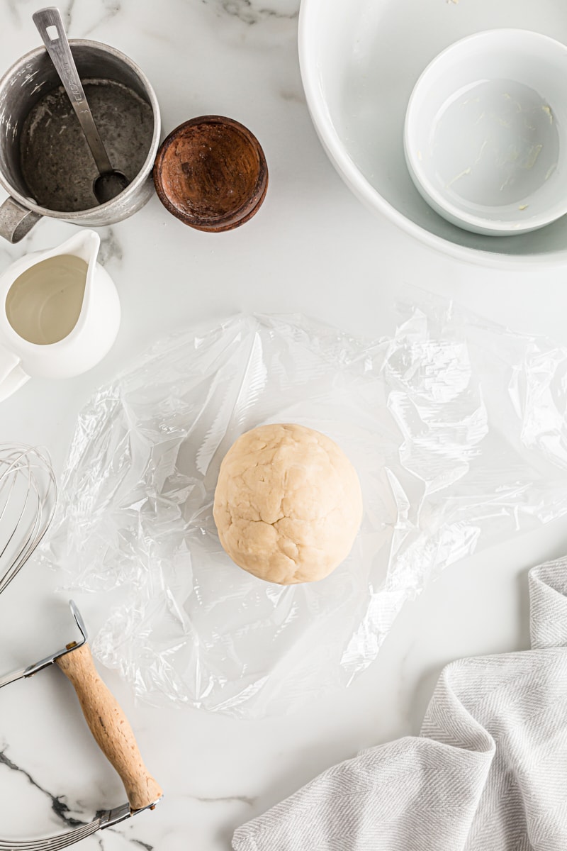 Overhead view of pie dough ball on plastic wrap