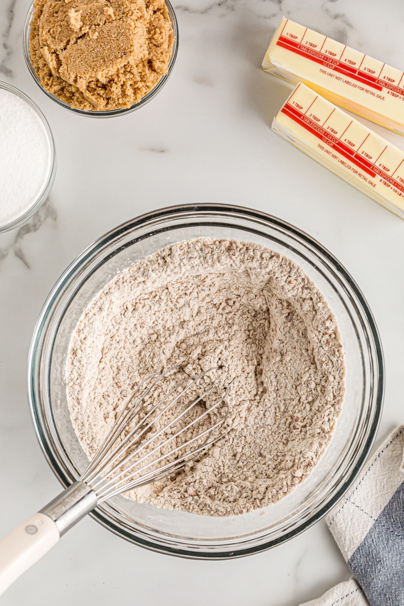 Dry ingredients for crust in glass mixing bowl with whisk