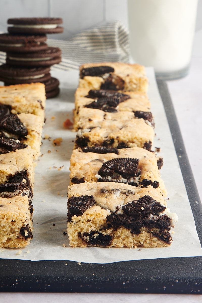 Cookies and Cream Blondies lined up on a cutting board covered in parchment paper