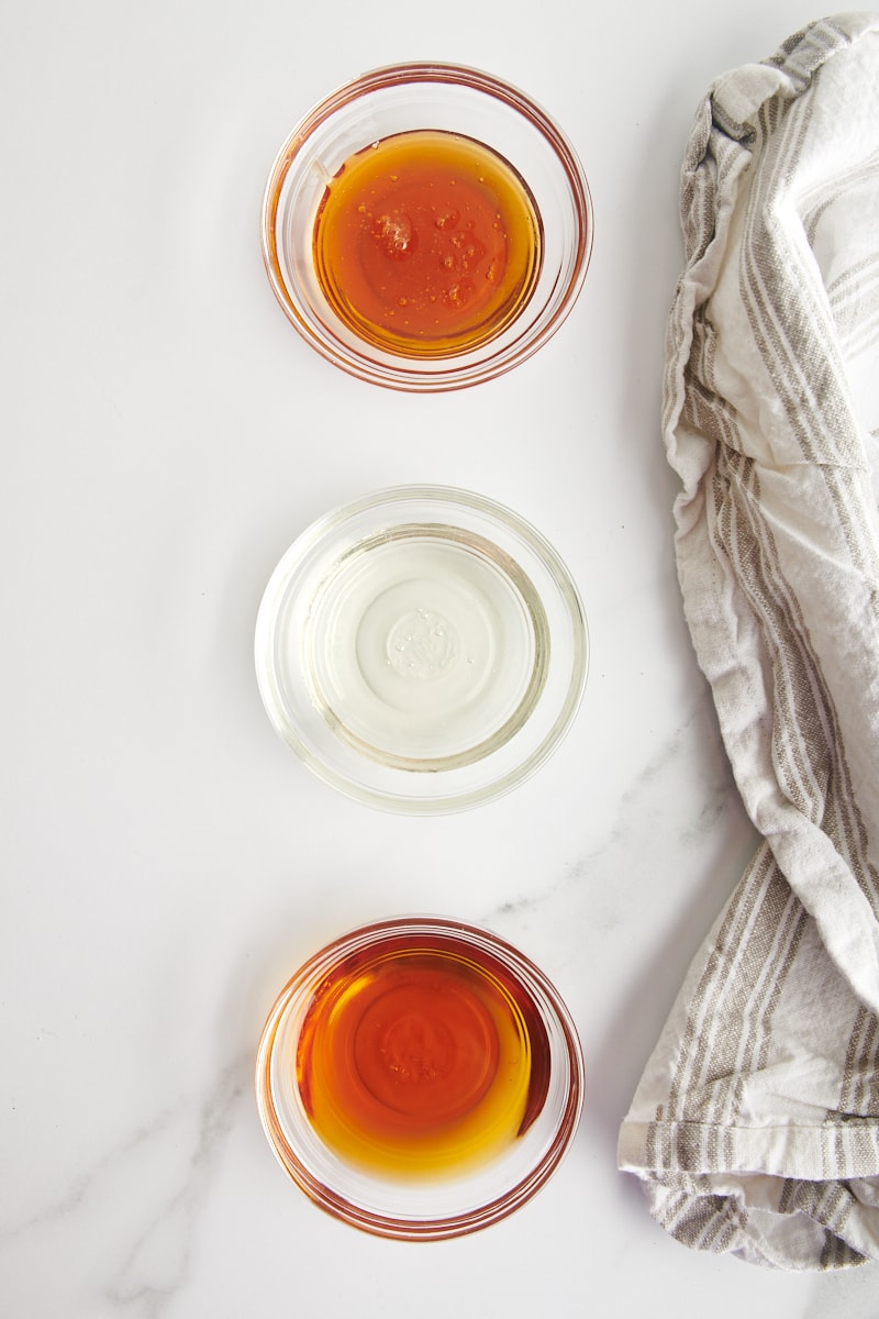 overhead view of honey, corn syrup, and maple syrup in small glass bowls