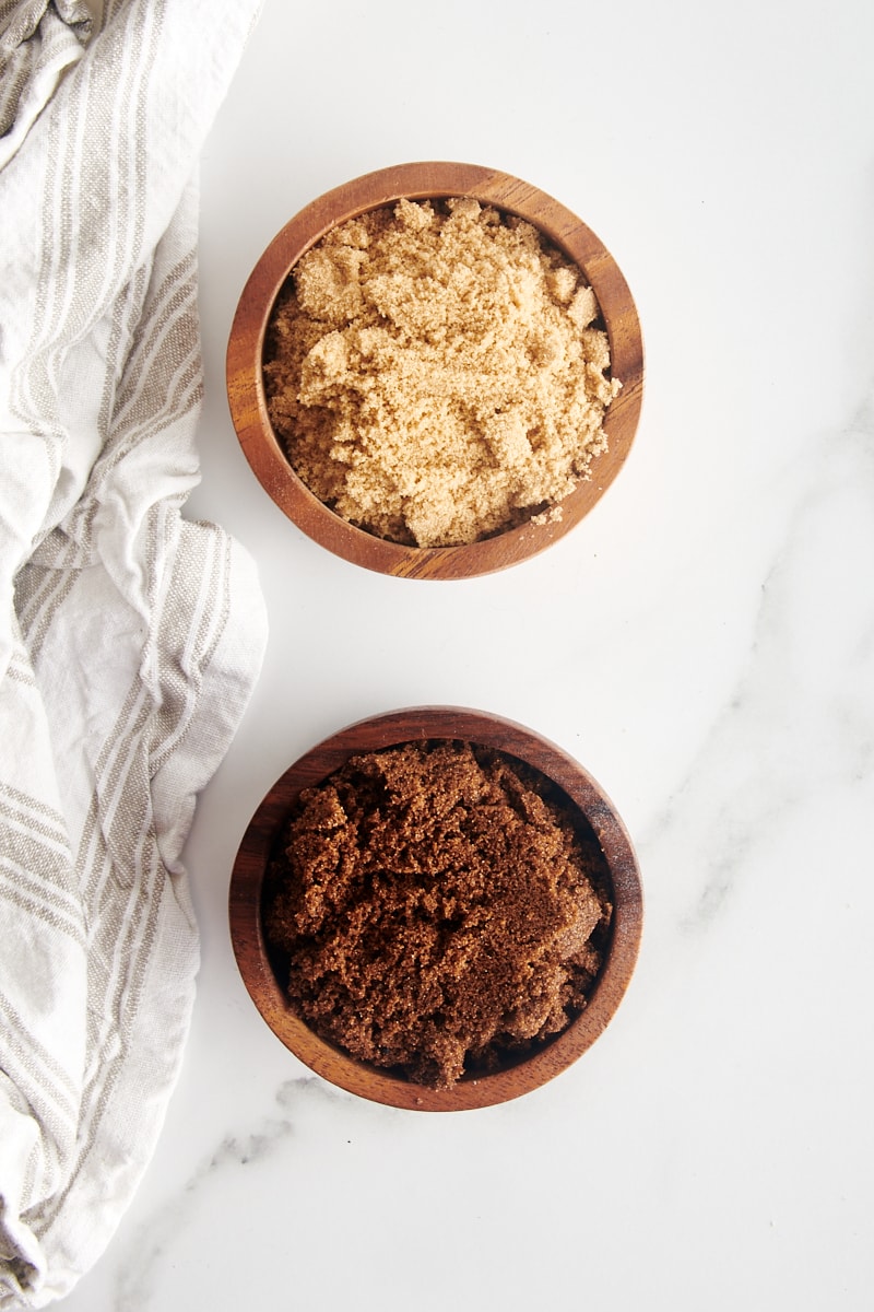 overhead view of light and dark muscovado sugars in small wooden bowls