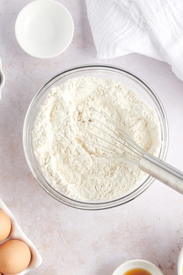 Overhead view of dry brownie ingredients in bowl with whisk