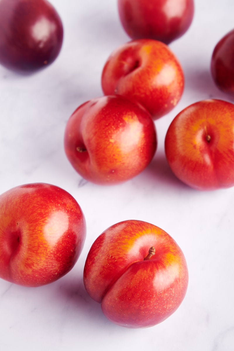 red plums scattered on a marble surface