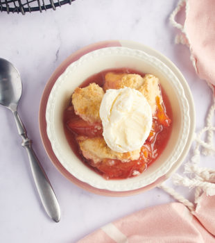 overhead view of a serving of plum cobbler in a white bowl