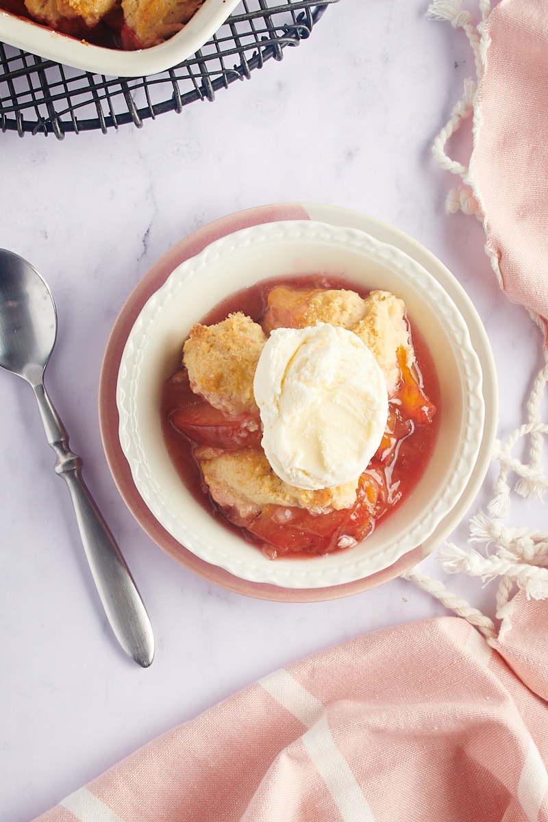 overhead view of a serving of plum cobbler in a white bowl