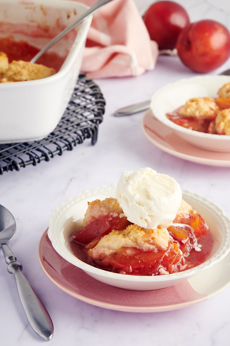 Plum Cobbler served in a white bowl with a scoop of ice cream