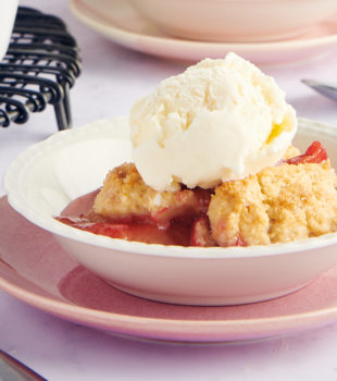Plum Cobbler served in a white bowl with a scoop of vanilla ice cream