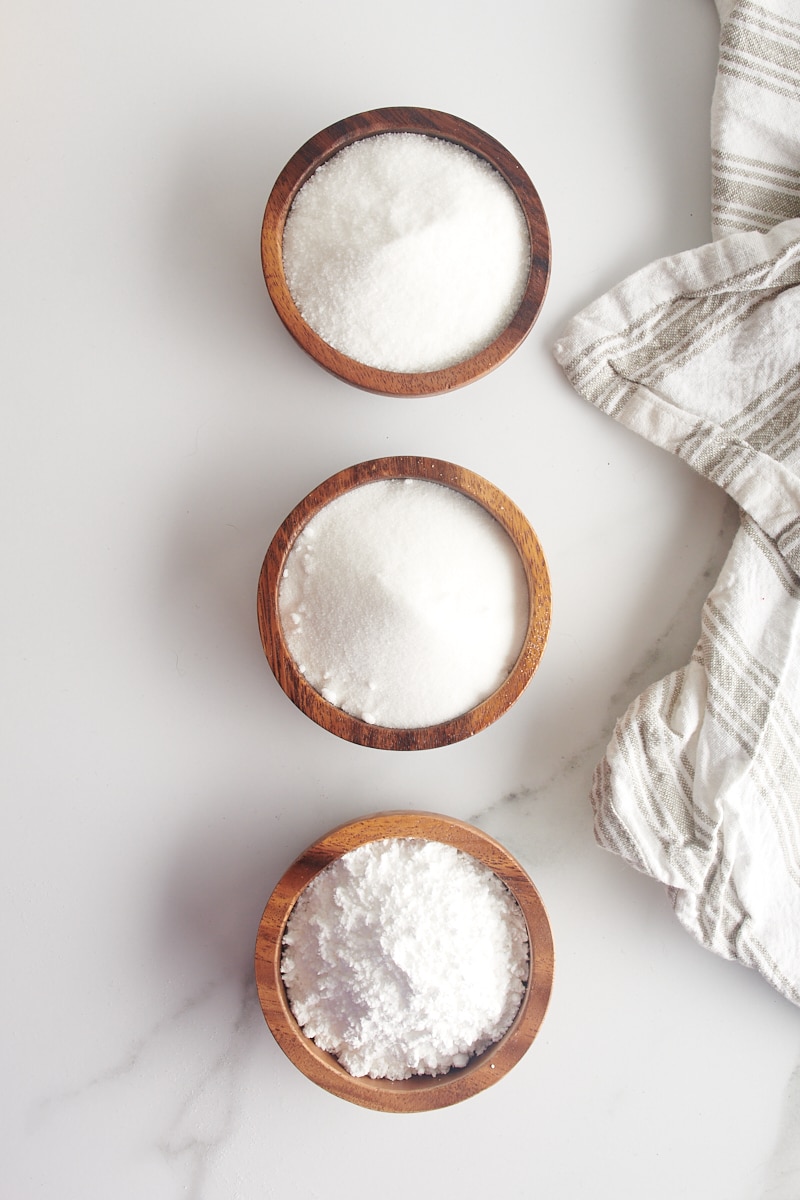 overhead view of granulated sugar, superfine sugar, and confectioners' sugar in wooden bowls