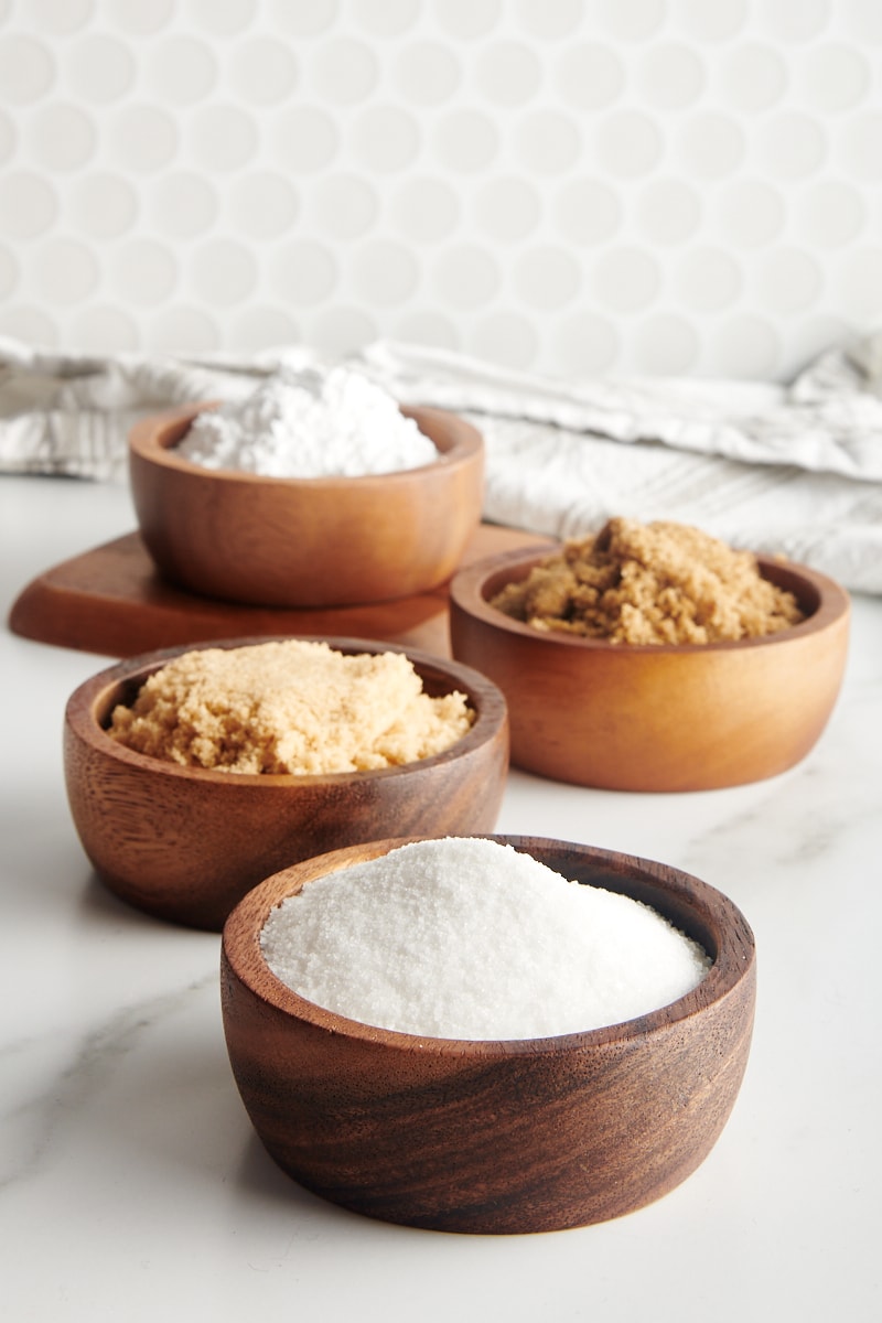 granulated sugar, light brown sugar, dark brown sugar, and confectioners' sugar in small wooden bowls