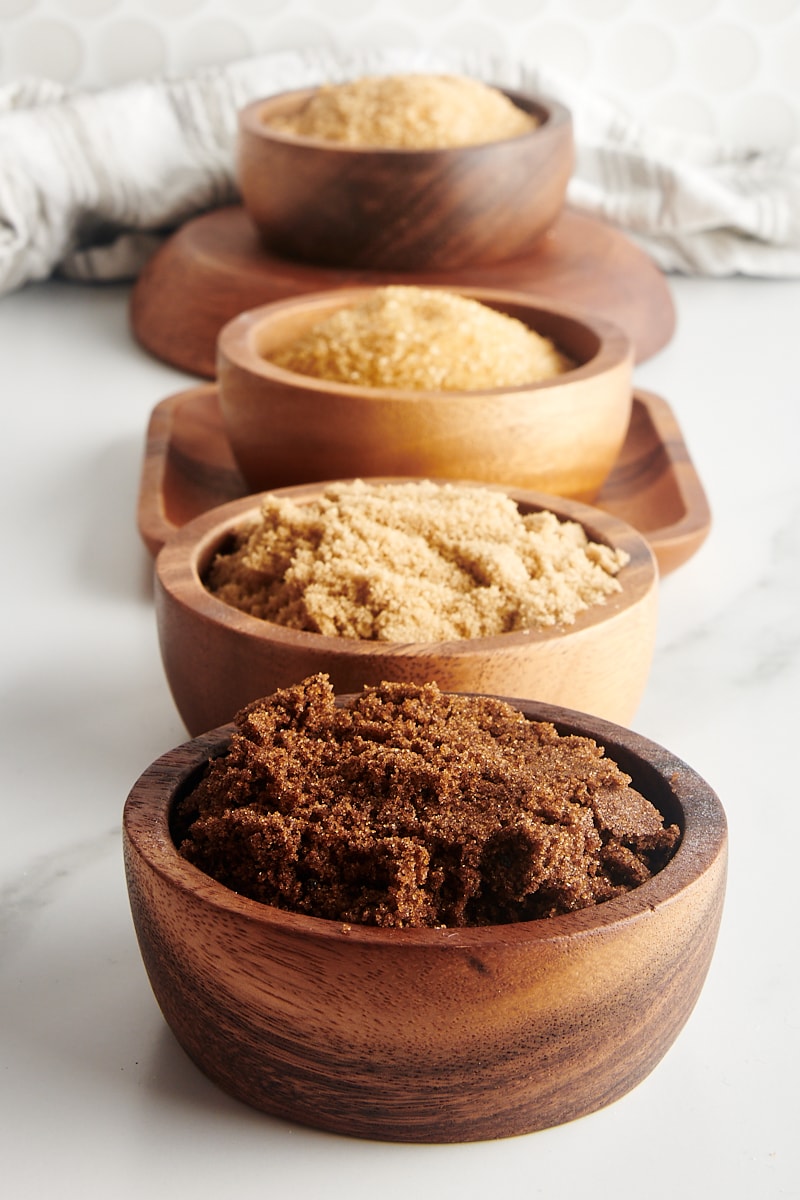 dark and light muscovado sugars, demerara sugar, and turbinado sugar in wooden bowls