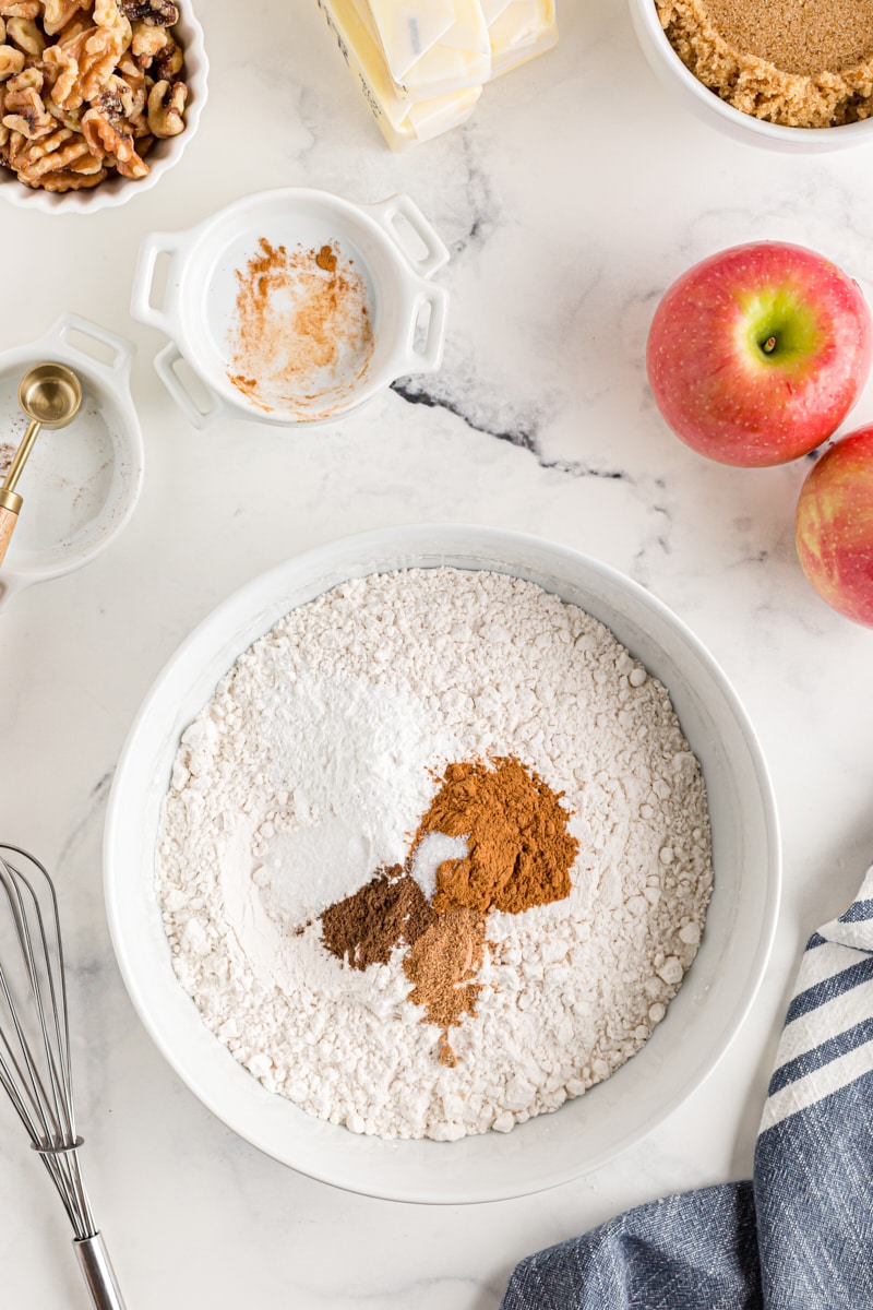 overhead view of dry ingredients for apple spice cake in a white mixing bowl