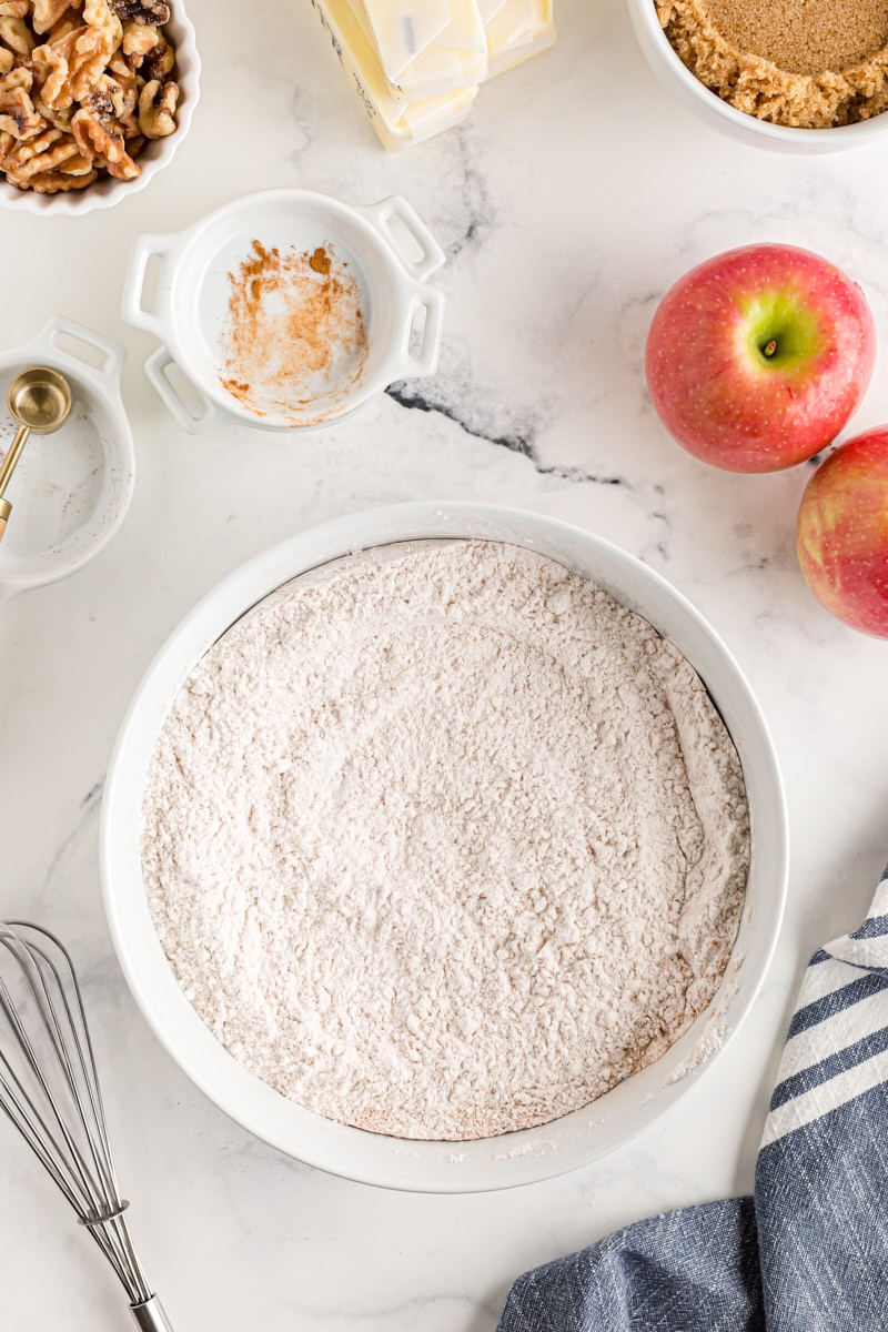overhead view of mixed dry ingredients for apple spice cake in a white mixing bowl