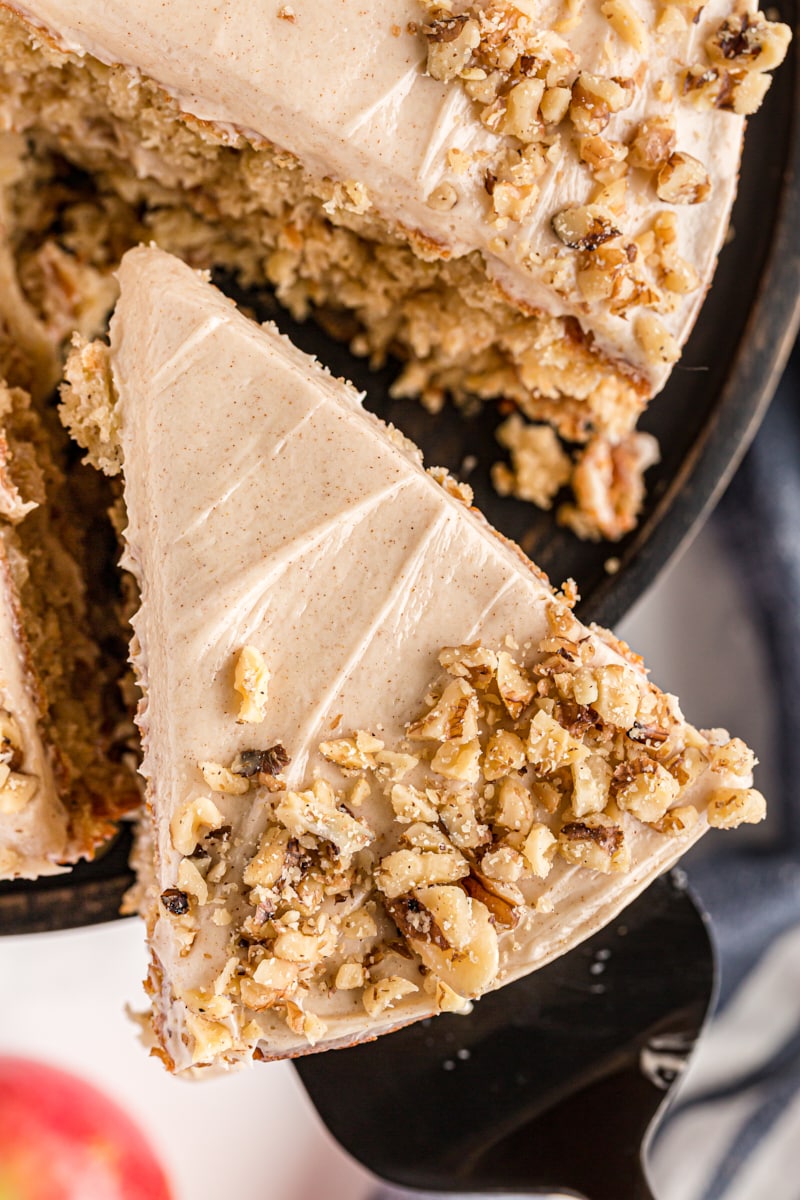 overhead view of a slice of apple spice cake on a cake server with remaining cake in the background