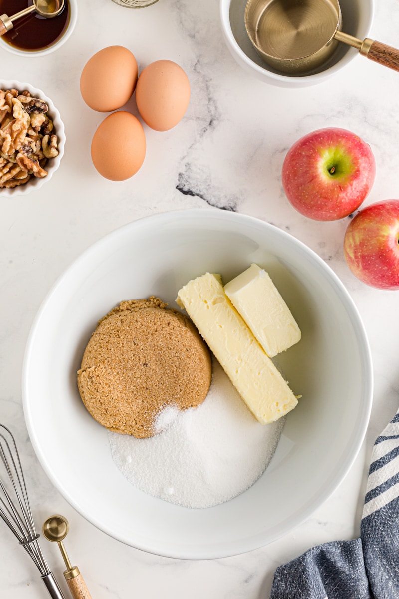 overhead view of butter, sugar, and brown sugar in a white mixing bowl