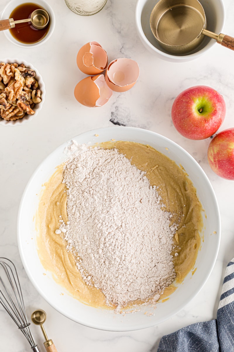 overhead view of dry ingredients added to wet ingredients for apple spice cake