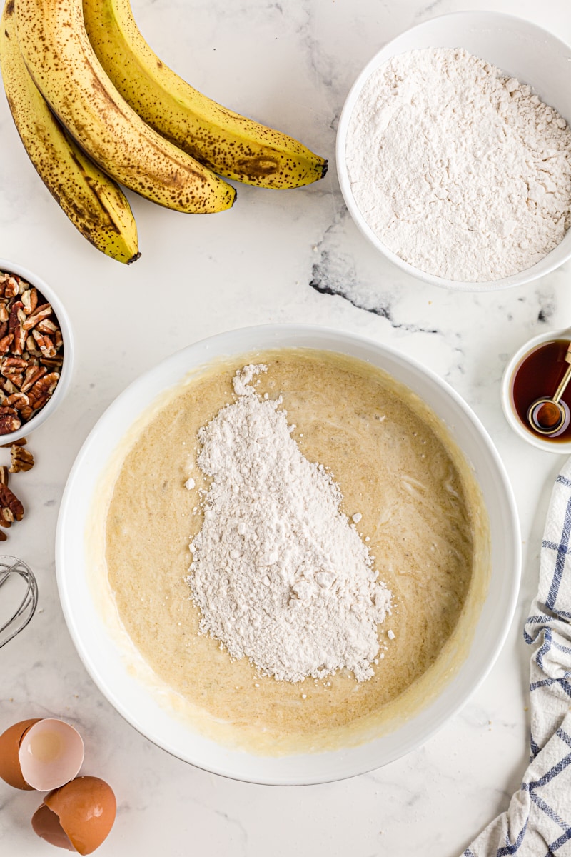 Overhead view of flour added to bowl of banana bar batter