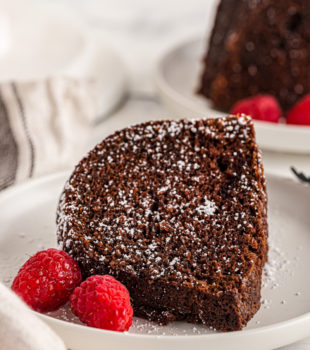 Slice of chocolate amaretto bundt cake on plate with raspberries