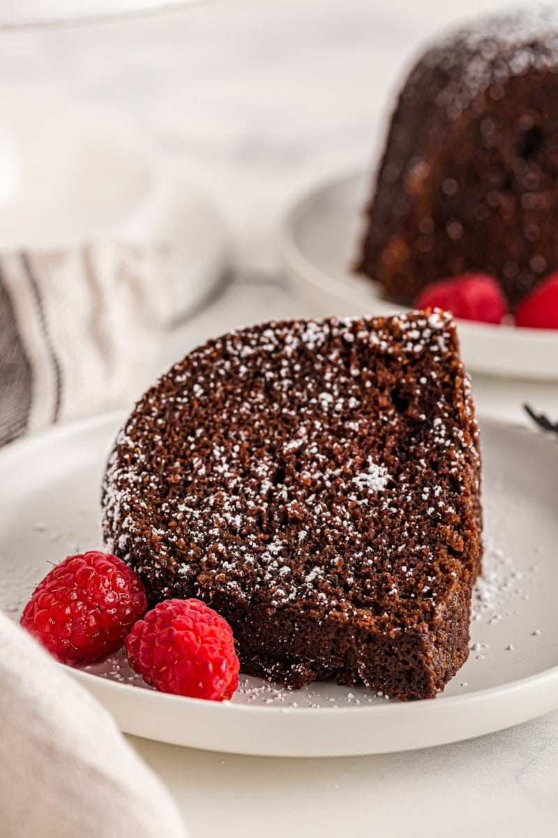 Slice of chocolate amaretto bundt cake on plate with raspberries