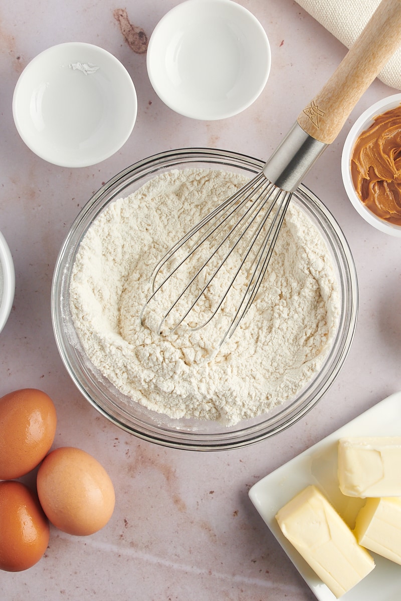 Overhead view of dry cupcake ingredients in mixing bowl with whisk