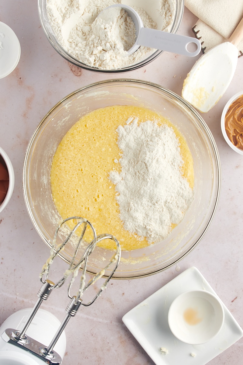 Overhead view of flour added to wet ingredients in bowl