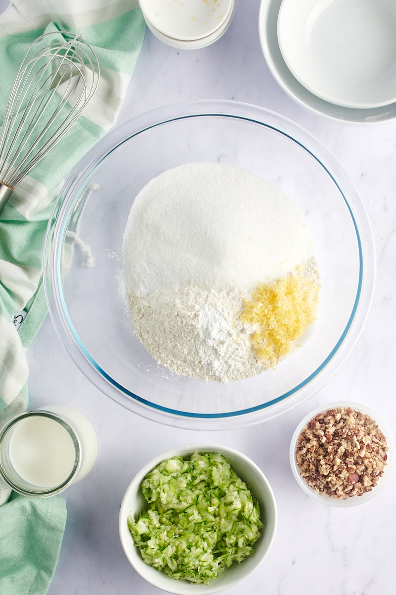 overhead view of flour, sugar, baking powder, baking soda, salt, and lemon zest in a glass mixing bowl