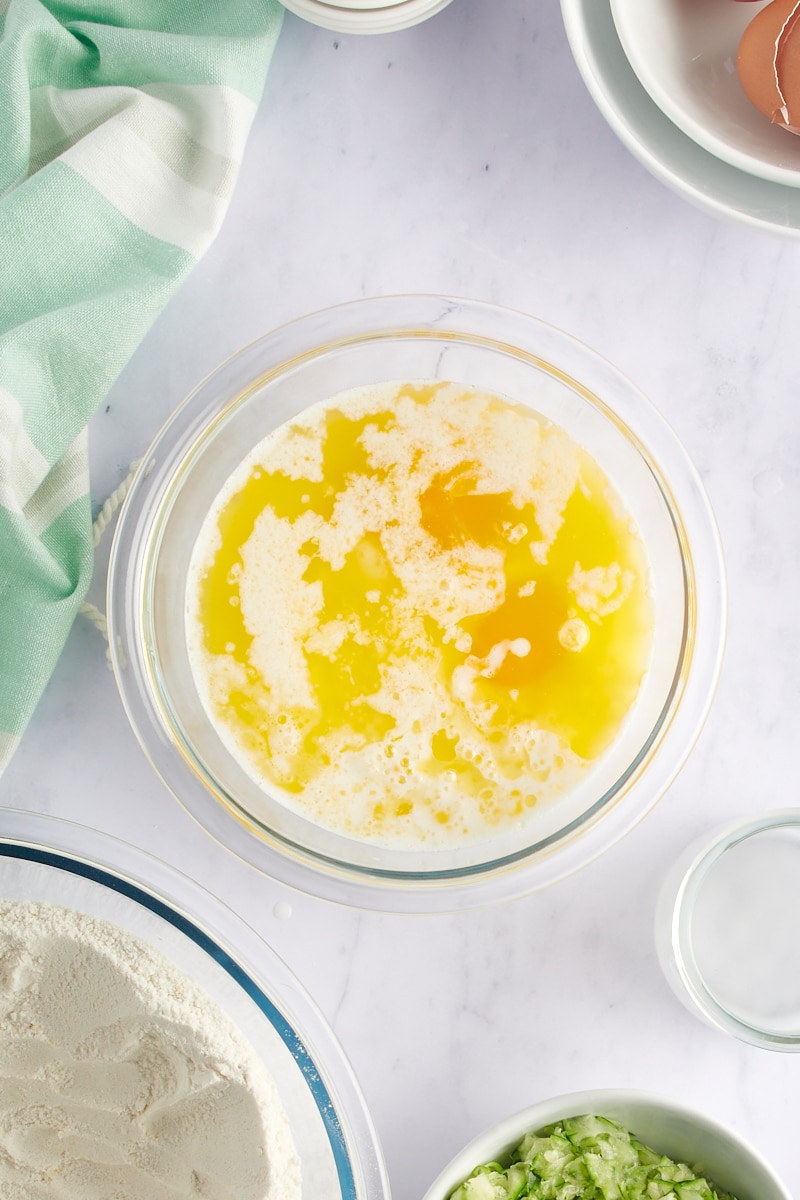 overhead view of melted butter, milk, eggs, and lemon juice in a glass mixing bowl