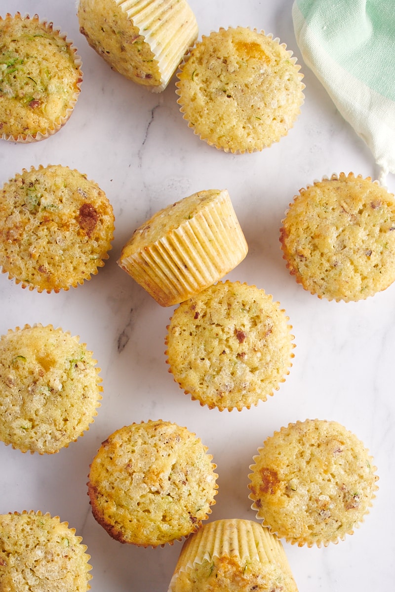 overhead view of Lemon Zucchini Muffins scattered on a marble surface