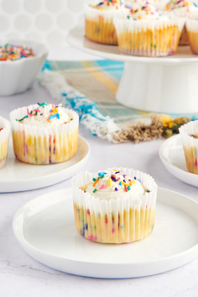 Mini Funfetti Cheesecakes on small white plates and a white pedestal