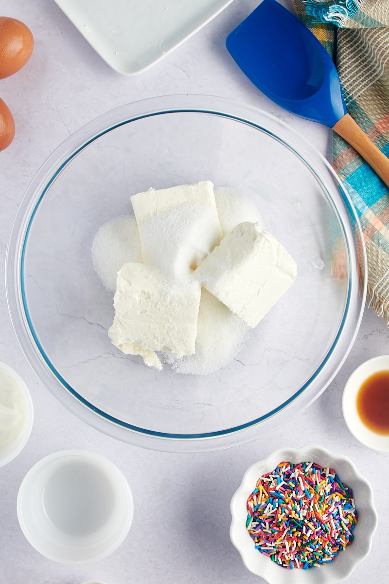 overhead view of cream cheese and sugar in a glass mixing bowl