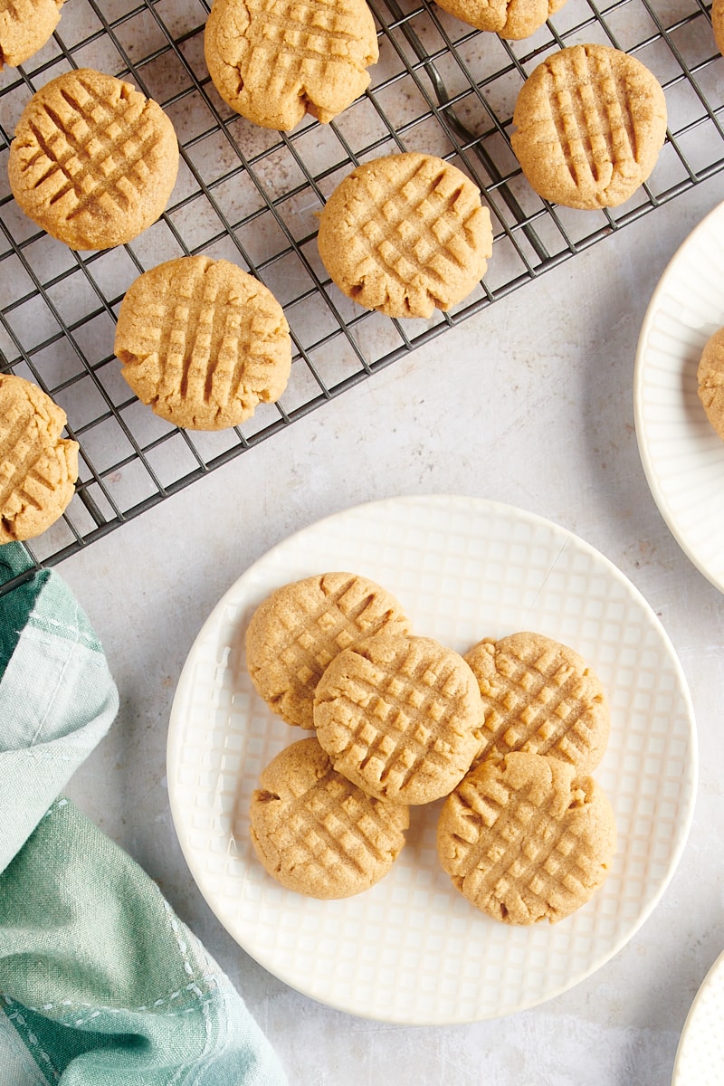 overhead view of 3-Ingredient Peanut Butter Cookies on a white and beige plate and on a wire rack