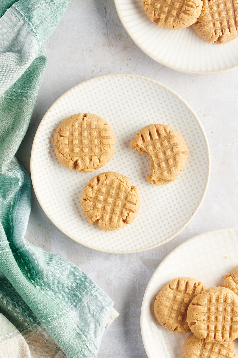 visão aérea de biscoitos de manteiga de amendoim com 3 ingredientes em pratos brancos e bege