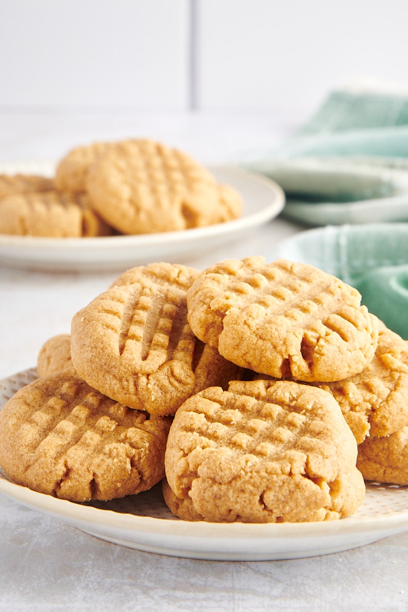 3-Ingredient Peanut Butter Cookies piled on a white and beige plate