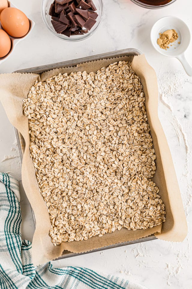 Oats spread out on a pan ready to be toasted.