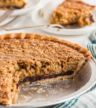 A black bottom oatmeal pie missing two slices which can be seen on plates in the background.
