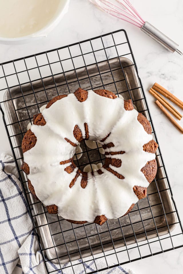 A freshly glazed Cinnamon Roll Cake on a cooling rack.