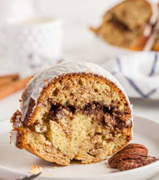 A slice of glazed cake on a plate with a cinnamon and brown sugar filling.