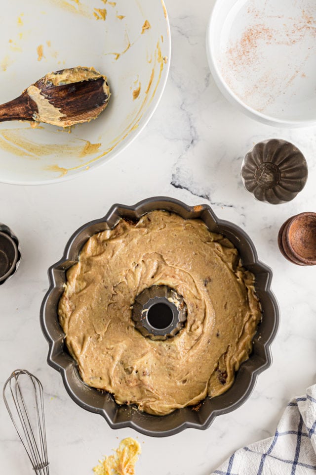 The second cake layer being smoothed out over the cinnamon filling in a Cinnamon Roll Cake.