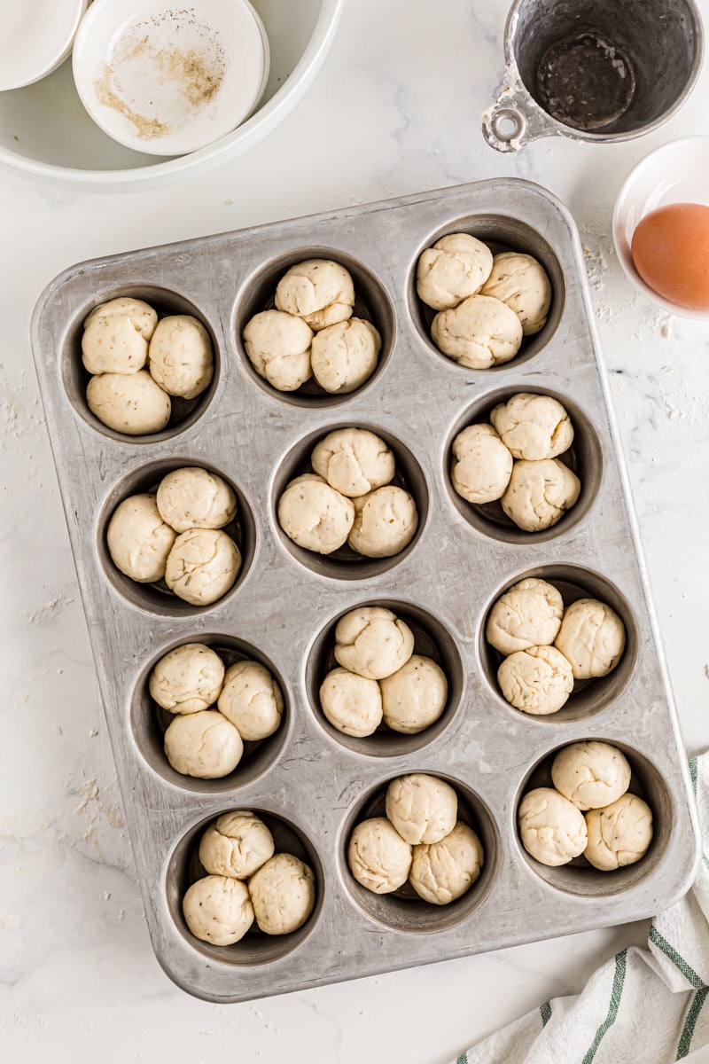 Three dough balls each in every cup of a muffin tin.