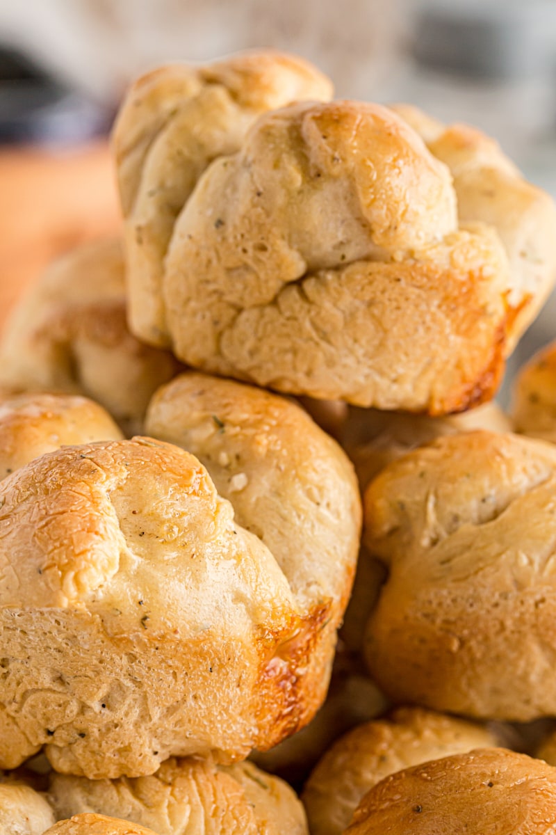 A pile of cloverleaf dinner rolls with herbs visible in the batter.