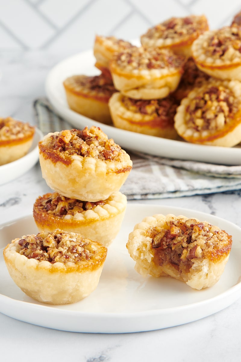 Two mini pies stacked on top of each other behind one whole mini pie and one with a bite taken out.