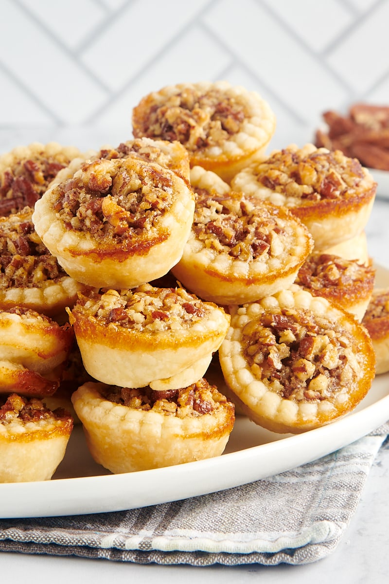 A pile of pecan mini pies on a large platter.