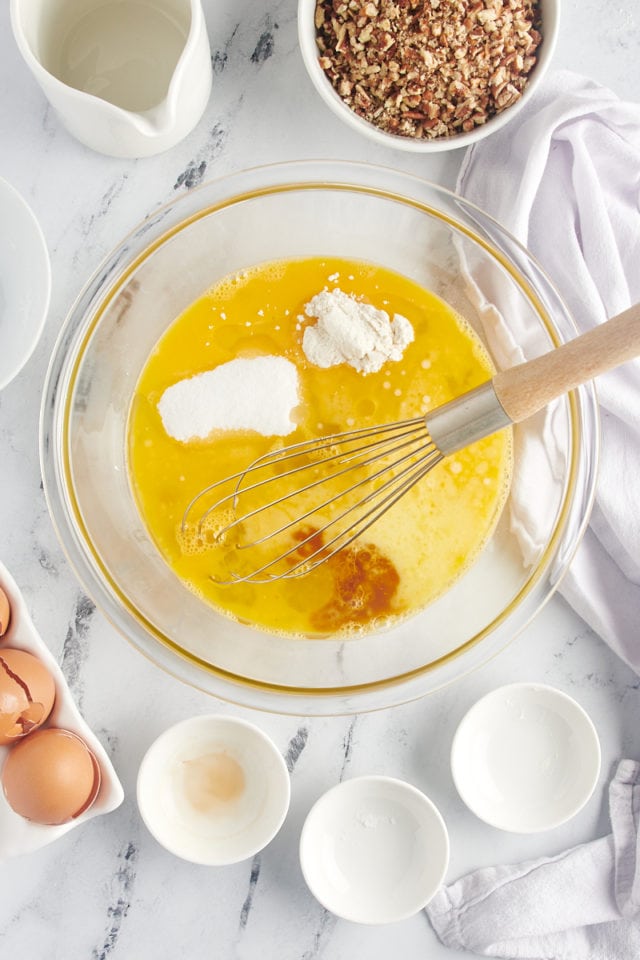 Sugar, corn syrup, butter, and flour being added to the whisked eggs.