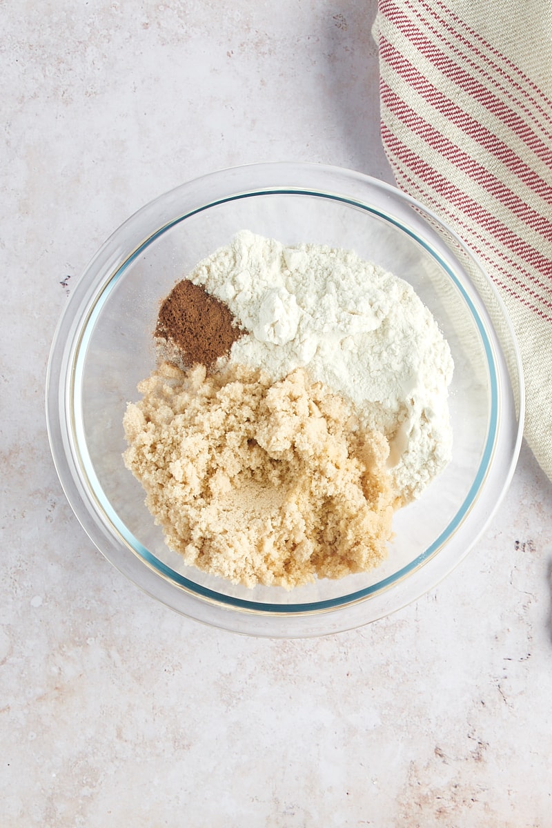 overhead view of flour, brown sugar, cinnamon, and salt in a glass mixing bowl